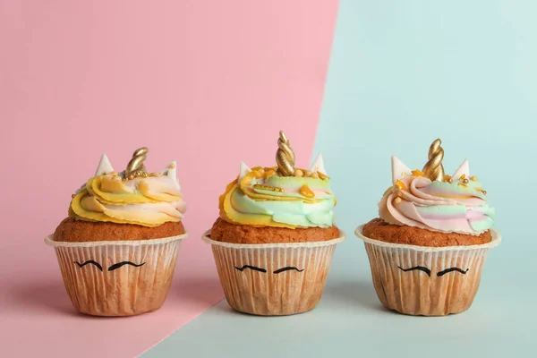 Cute sweet unicorn cupcakes on color background