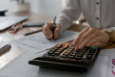 Hesap makinesi olan bir vergi muhasebecisi ofiste çalışıyor, yakın plan.