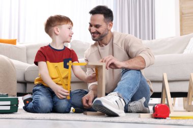 Baba ve oğul evde rafları birlikte ölçüyorlar. Onarım işi