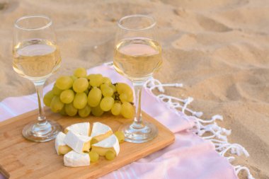 Beyaz şaraplı bardaklar ve kumsalda piknik yapmak için atıştırmalıklar.