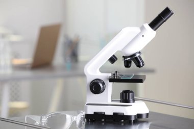 Modern medical microscope on metal table in laboratory, space for text