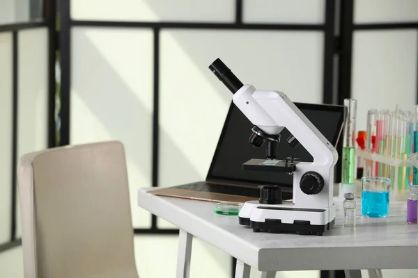 Modern microscope with glass slide on white table in laboratory, space for text