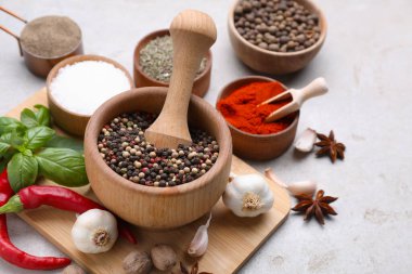 Açık gri masadaki topuzlu ve farklı baharatlı havan topu.