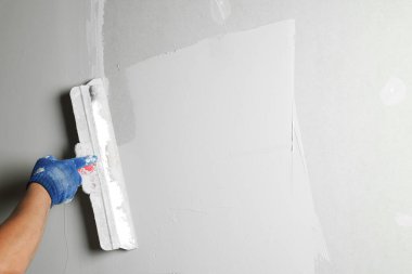 Profesyonel işçi duvar macun bıçağıyla sıva yapıyor, yakın plan.