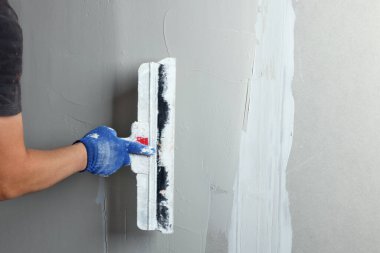 Profesyonel işçi duvar macun bıçağıyla sıva yapıyor, yakın plan.