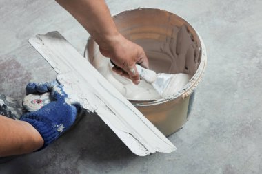 Profesyonel işçi kapalı alandaki kovadan alçı alıyor, yakın plan.