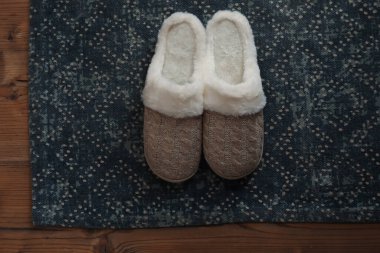 Şık bir kapı paspası ve ahşap zemin üzerinde terlikler.