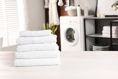 Çamaşır odasındaki beyaz masaya temiz havlu yığını, mesaj atmak için yer.