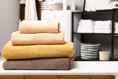 Çamaşır odasındaki beyaz masaya temiz havlu yığını, mesaj atmak için yer.