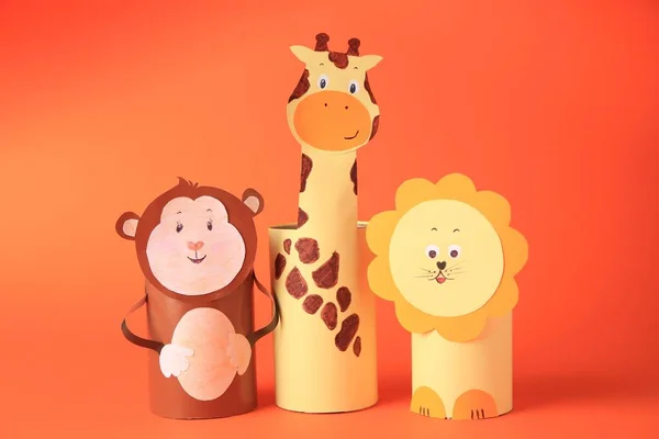 Toy monkey, giraffe, and lion made from toilet paper hubs on orange background. Children\'s handmade ideas