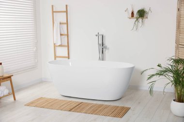 Seramik küvet ve ev bitkileriyle dolu şık bir banyo.