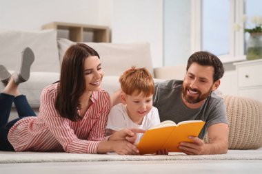 Mutlu ebeveynler ve çocukları evde kitap okuyorlar.