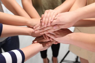 Group of people holding hands together indoors, closeup. Unity concept