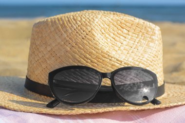 Güneş gözlüklü güzel şapka, deniz kenarında battaniye, yakın çekim.