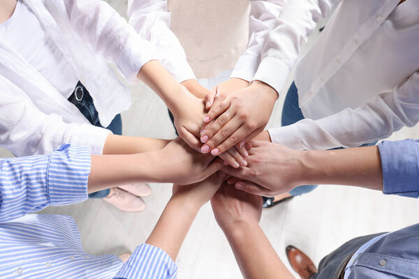 Группа людей, держащихся за руки в помещении, над видом. Концепция единства