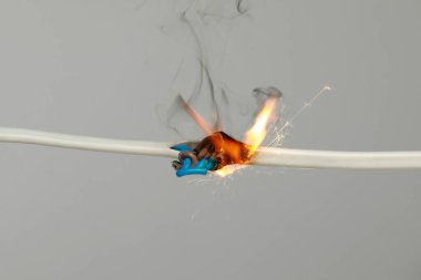 Gri arka planda iltihaplı beyaz kablo, yakın plan. Elektrik kısa devresi