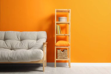 Havalı bej kanepe ve turuncu duvarın yanında ahşap askı. İç tasarım