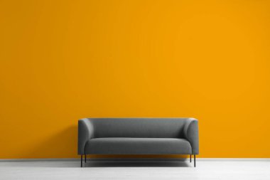 Turuncu duvarın yanındaki şık gri kanepe, yazı için yer. İç tasarım