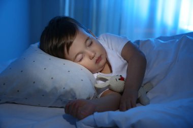Evde oyuncakla uyuyan şirin bir bebek. Yatma zamanı.