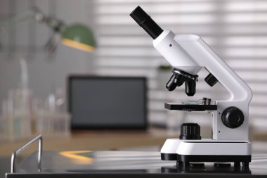 Modern medical microscope on metal table in laboratory, space for text
