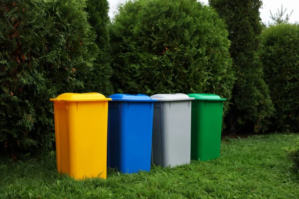 Many color recycling bins on green grass outdoors, space for text