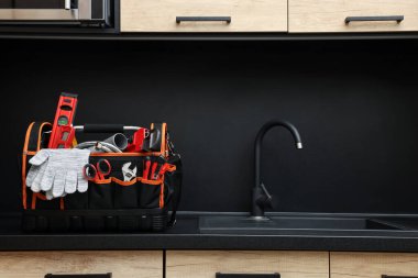 Tesisatçı alet çantası mutfak tezgahında lavabonun yanında.
