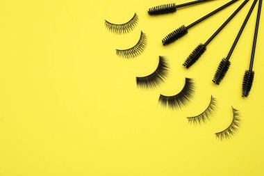 Sarı arka planda takma kirpikler ve fırçalar. Metin için boşluk
