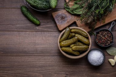 Bir kase salatalık turşusu ve ahşap masa üzerindeki malzemeler. Metin için boşluk