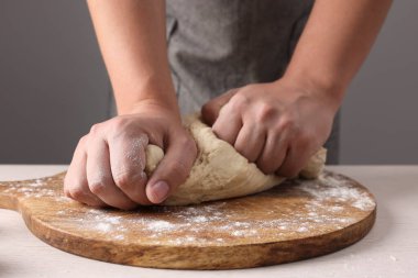 Gri duvarın yanındaki masada hamur yoğuran adam, yakın plan.