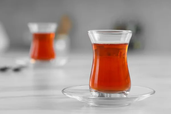 Glass of traditional Turkish tea on white marble table, space for text