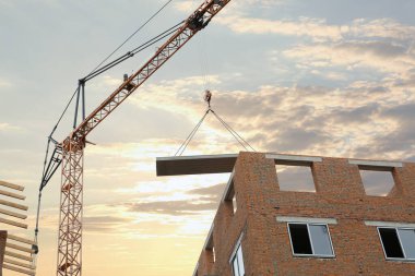 Construction site with tower crane near unfinished building, low angle view