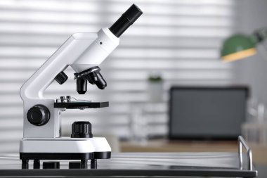 Modern medical microscope on metal table in laboratory, space for text
