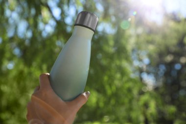 Güneşli bir günde parkta termosu olan bir adam, yakın plan. Metin için boşluk