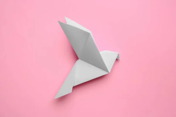 Beautiful origami bird on pink background, flat lay