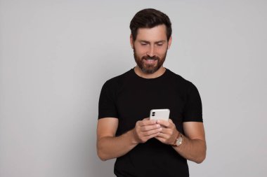 Hafif arka planda akıllı telefonu olan mutlu bir adam.