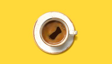 Sarı arka planda beyaz bardakta Aromatik kahve, üst manzara.