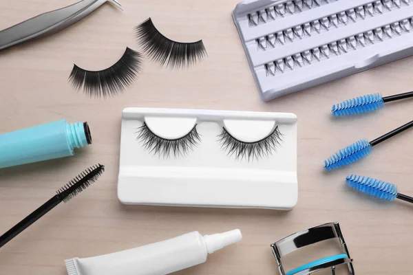 Flat lay composition with false eyelashes and tools on wooden table