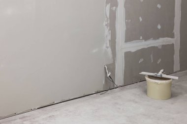 Kapalı alanda duvarın yanında macun bıçağı olan kova.