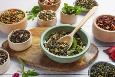 Beyaz ahşap masada birçok farklı bitki çayı var.
