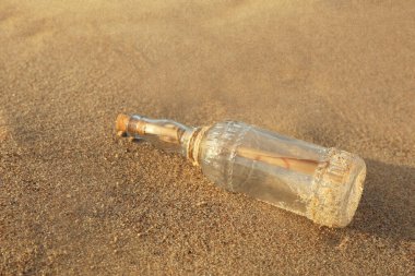 Kumda cam şişe içinde SOS mesajı, yakın plan.