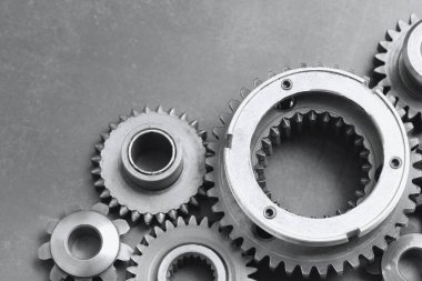 Gri arka planda farklı paslanmaz çelik dişliler, yakın plan. Metin için boşluk