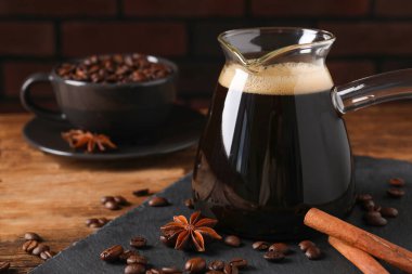 Cam kafeste Türk kahvesi, ahşap masada fasulye ve baharatlar. Metin için boşluk