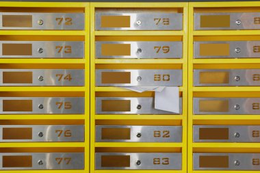 İçerideki postaneden gelen makbuzlarla dolu metal posta kutuları.