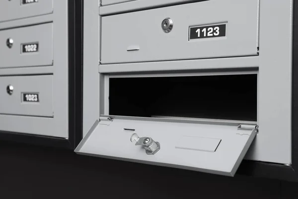 Open empty grey metal mailbox with keyhole indoors