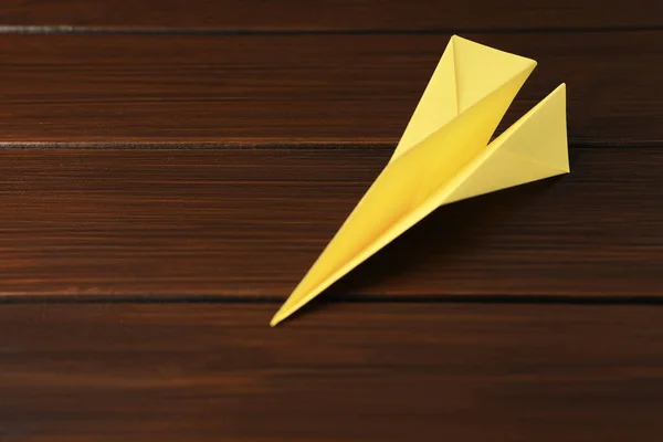 Handmade paper plane on wooden table, closeup. Space for text