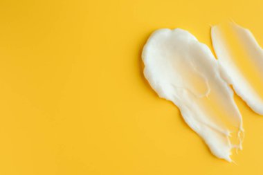 Sarı arka planda yüz kremi örnekleri, üst manzara. Metin için boşluk