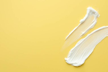 Sarı arka planda yüz kremi örnekleri, üst manzara. Metin için boşluk