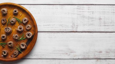 Beyaz ahşap masada biberiyeli konserve ançüez fileto. Metin için boşluk