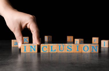 Koyu gri masada siyah arka planda tahta küplerle kelime oyunu yapan bir kadın. Metin için boşluk