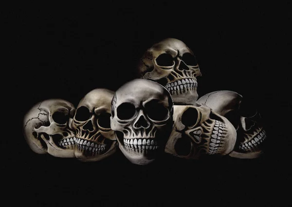 Pile of scary human skulls on black background